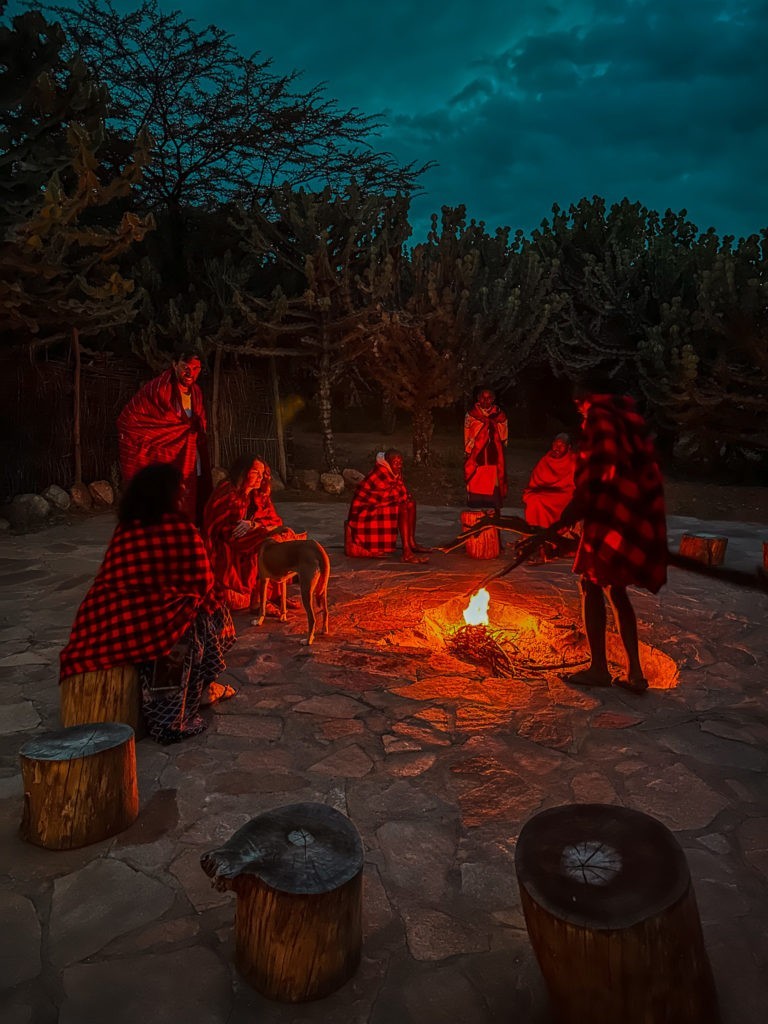 People sitting at a fireside in Maji Moto Maasai Cultural Camp
