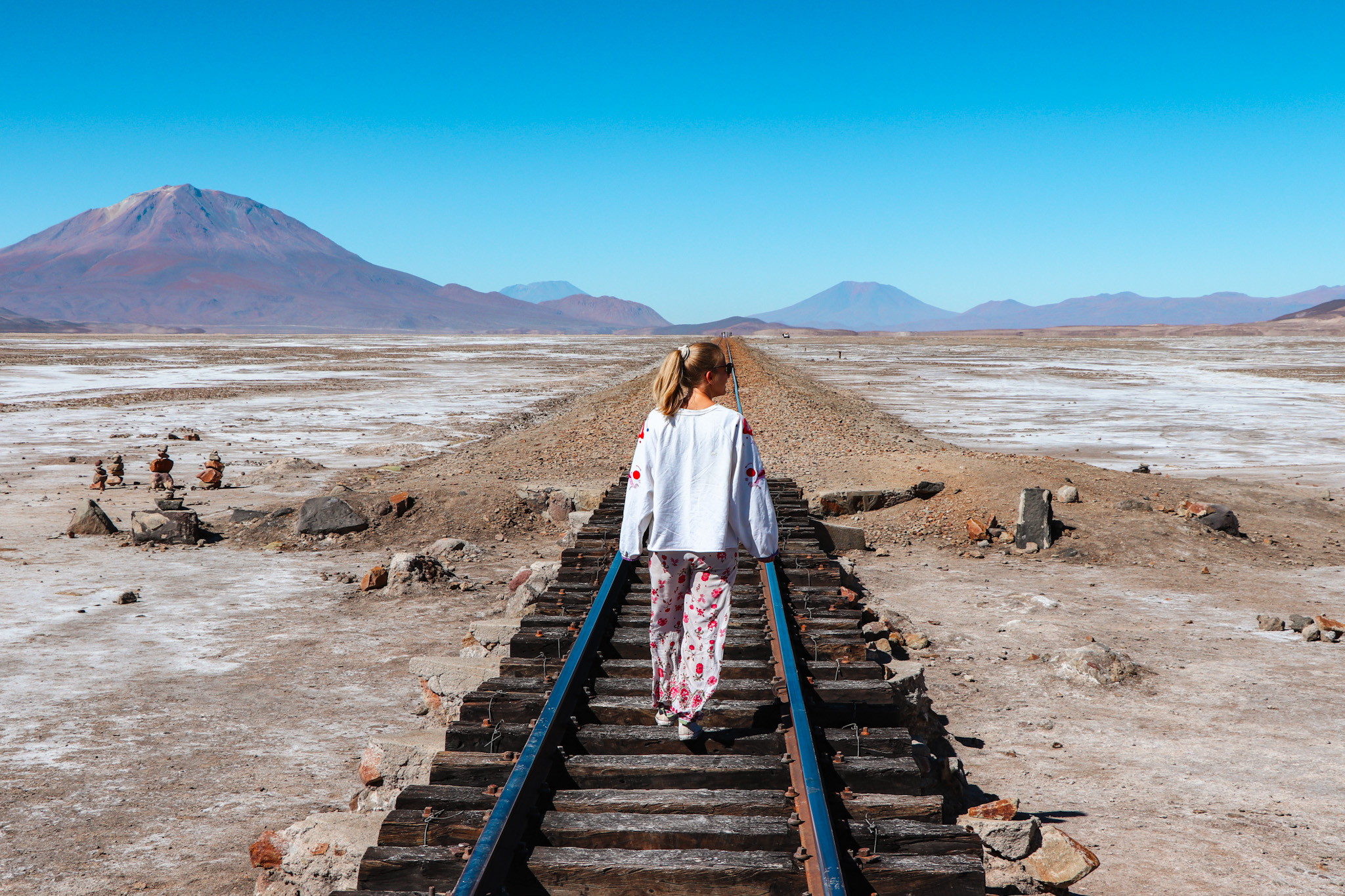 Uyuni Travel Guide: Walking on the train tracks leading to Chile in Salar de Chiguana with volcano Ollagüe in the background